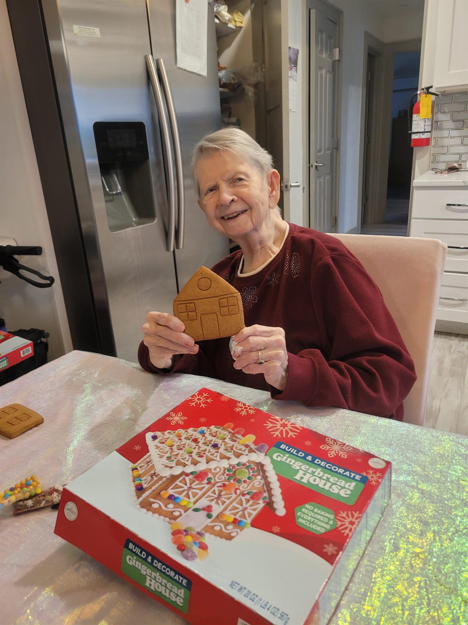 A resident holding a wall of a gingerbread house before assembling it