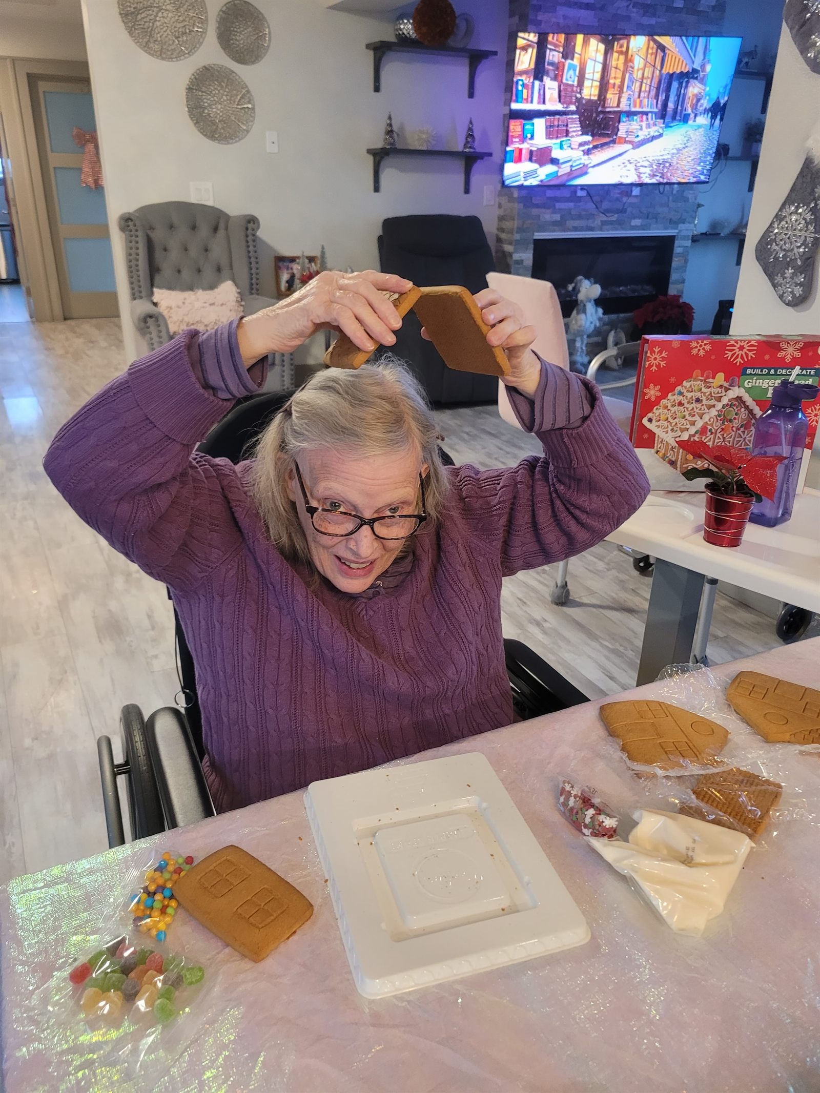 A resident laughing while holding two gingerbread pieces above her head